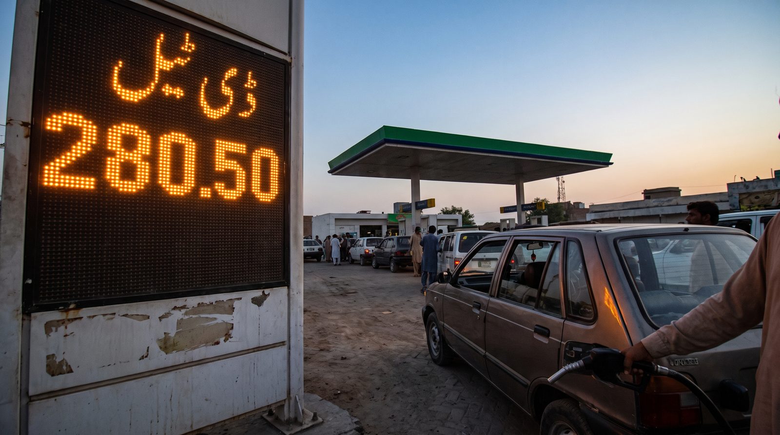 A Pakistani fuel station price display board at dusk showing a freshly updated diesel rate